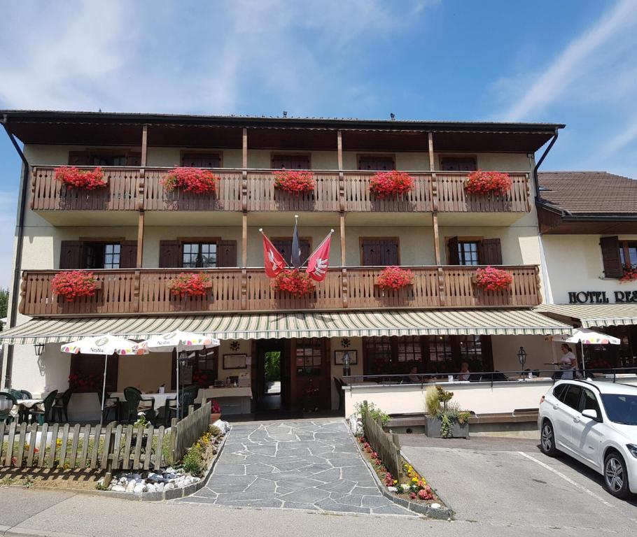 a building with a balcony with red flowers on it at Hôtel Restaurant le Gruyérien in Morlon