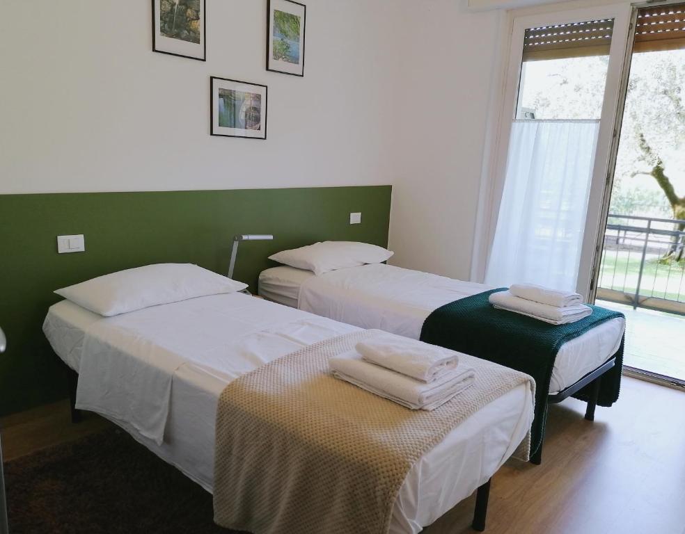 two beds in a room with a window at Olive Tree House in Riva del Garda