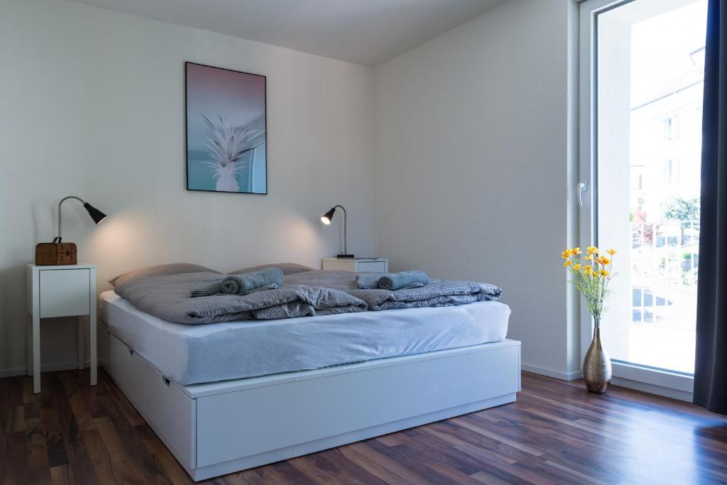 a white bedroom with a bed with blue sheets at HITrental Wiedikon Apartments in Zürich