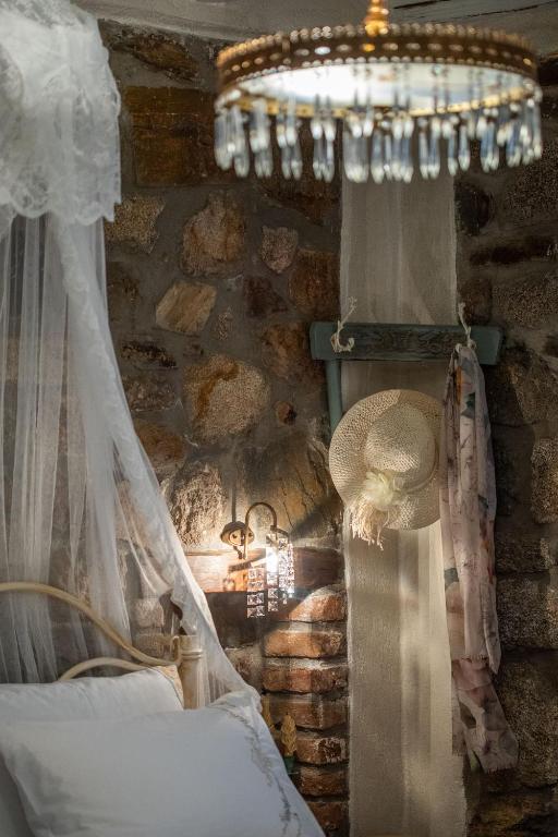 a bedroom with a stone wall with a chandelier at Ta Petrina in Vourvourou