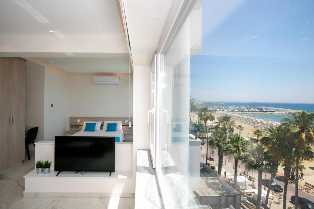 a living room with a television and a view of the beach at Les Palmiers Sunorama Beach Apartments in Larnaka