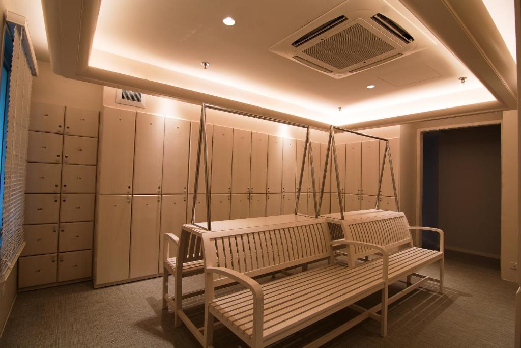 A warm-lit changing room with lockers, benches and an air-conditioning unit.