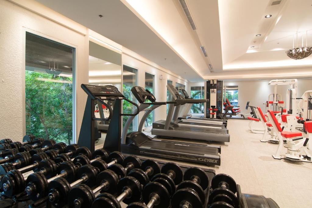 A bright fitness room with treadmills, dumbbells, and resistance machines.