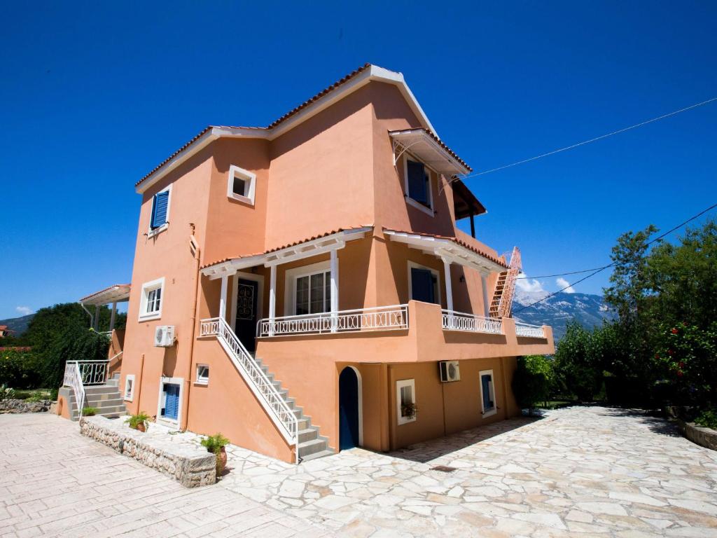 a large orange house with stairs on a stone driveway at Studios Dimitra in Spartià