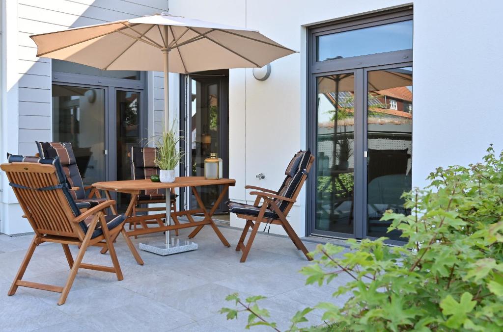 a patio with a table and chairs and an umbrella at Ferienwohnung TreibGood in Glowe