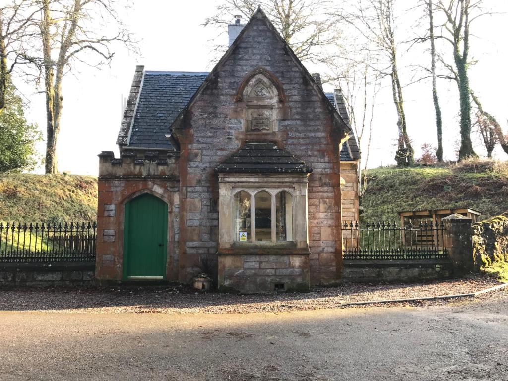 una vieja casa de ladrillo con una puerta verde en North Lodge, en Invergarry