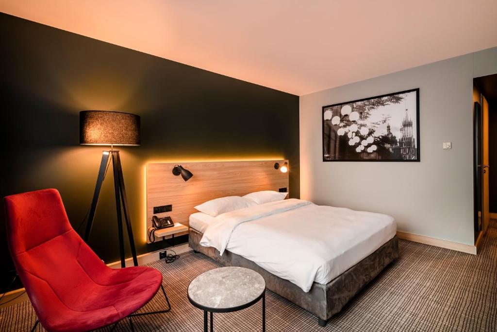 a bedroom with a bed, chair, lamp and a desk at Park Inn by Radisson Krakow in Kraków