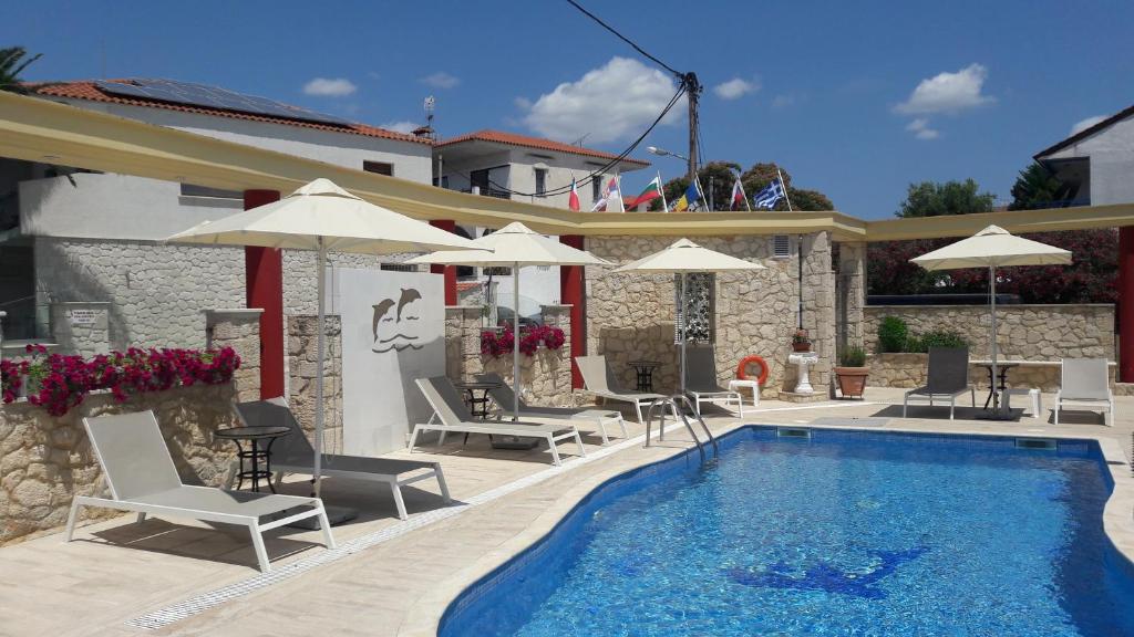 a swimming pool with chairs and umbrellas next to a building at Hotel Venus in Fourka