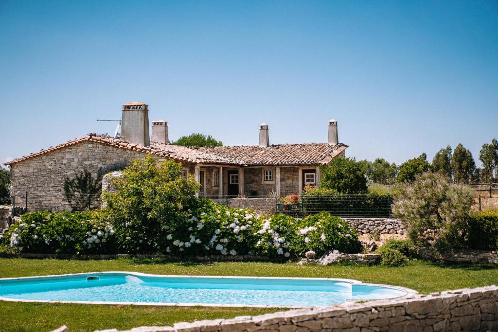 une maison avec une piscine en face de celle-ci dans l'établissement Casas de Pedra - Quinta da Escola, à Alvados