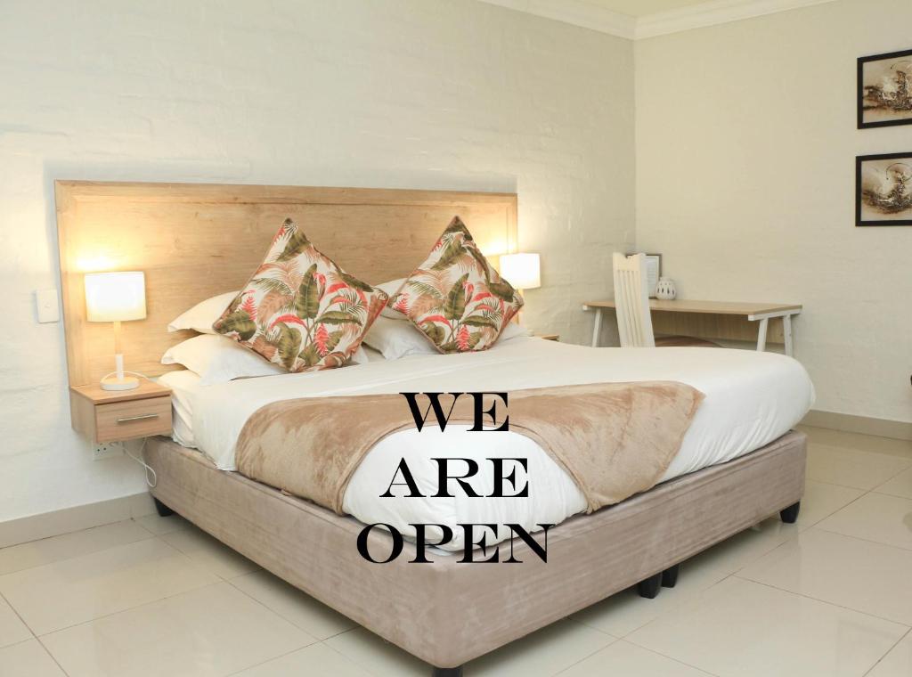 a bedroom with a bed with a we are open sign on it at The Milkwood Beach Apartments in Amanzimtoti