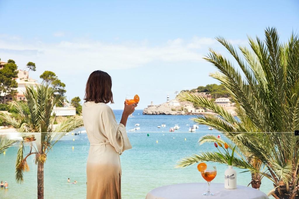 uma mulher segurando copos de vinho com vista para a praia em Hotel Boutique Minister 4Sup em Port de Sóller