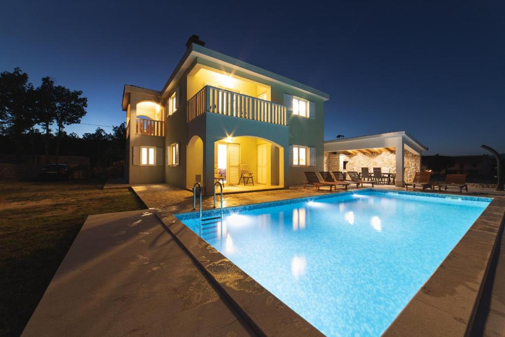 eine Villa mit einem Pool in der Nacht in der Unterkunft Villa Green Oasis in Lovreć