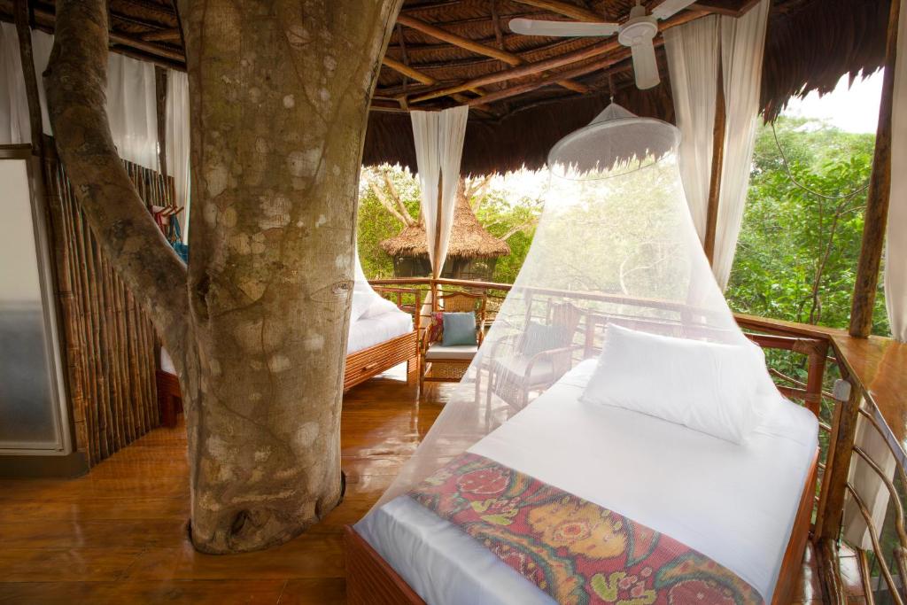um quarto com uma cama e uma árvore em Treehouse Lodge em Yucuruche