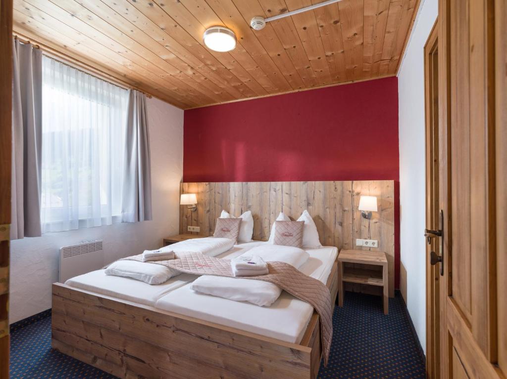 a bedroom with a large bed with a red wall at Haus Tirol in Brixen im Thale
