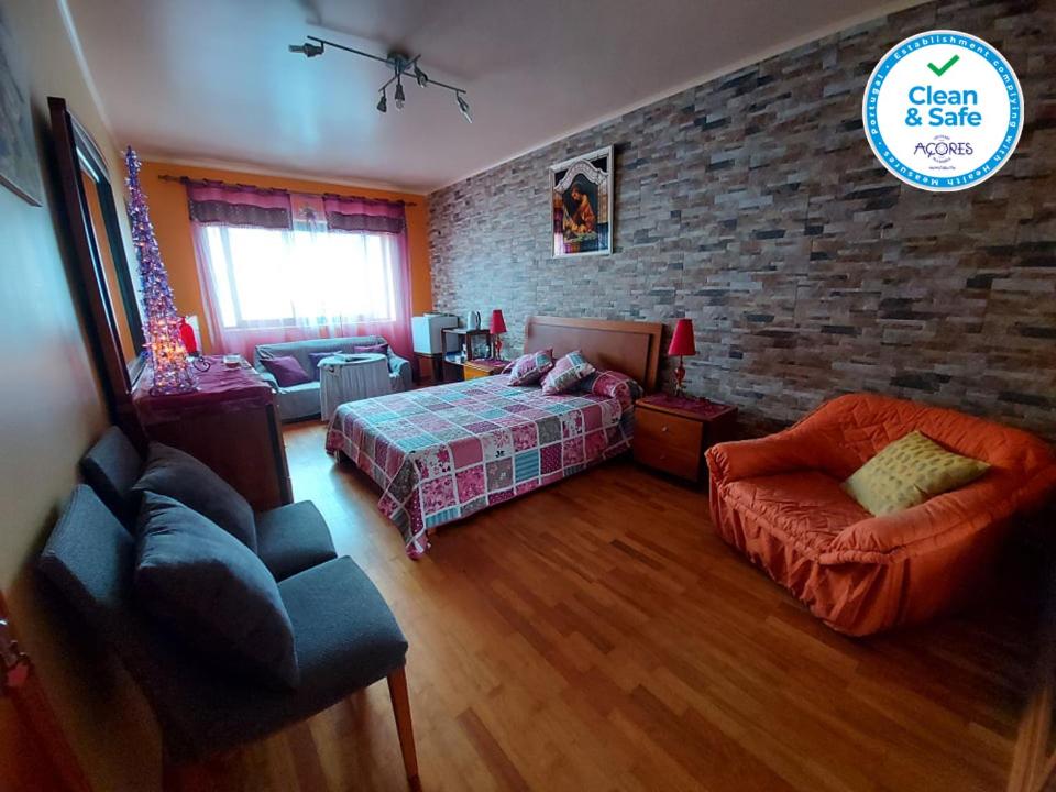 a bedroom with a bed and a brick wall at Nelocas House in Ponta Delgada