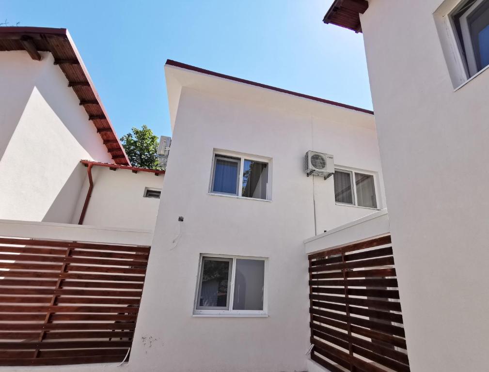 a white house with wooden doors and windows at Apartamente Liliacul in Jupiter