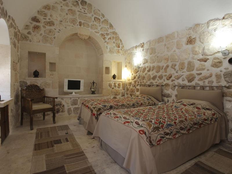 a bedroom with two beds and a stone wall at Kasr-i Nehroz Hotel in Midyat