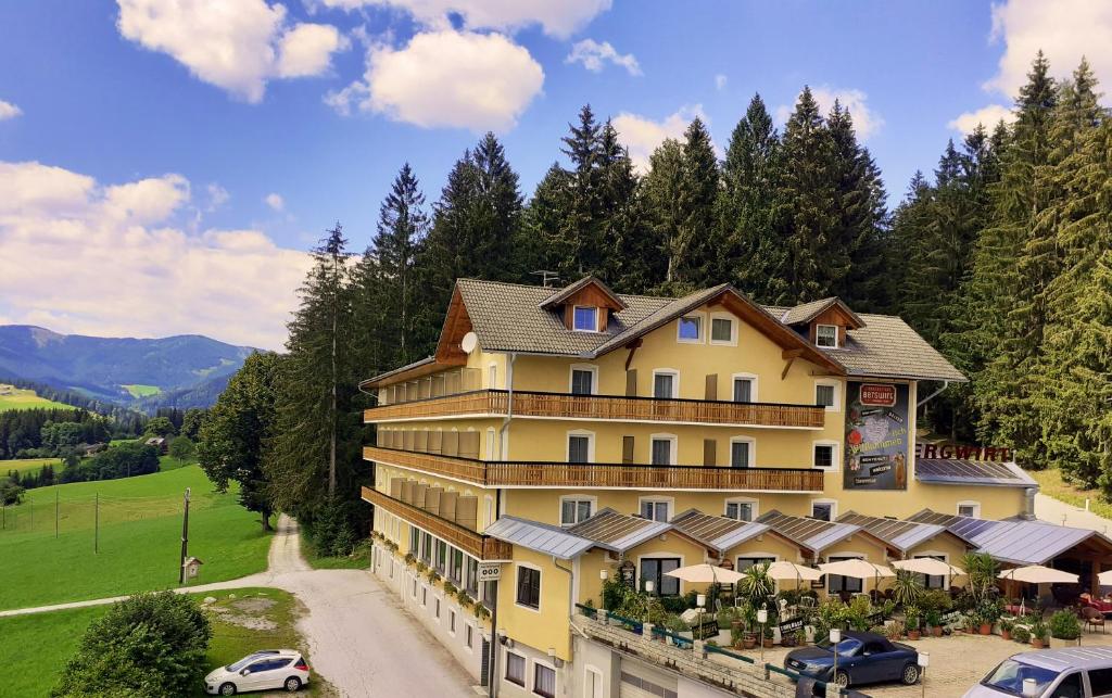 a large yellow building with cars parked in front of it at LiebesNesterl Bergwirt - Boutique Hotel in Köflach