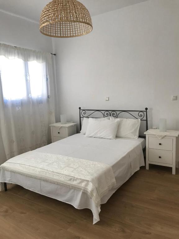 - une chambre dotée d'un lit avec des draps blancs et un lustre dans l'établissement Vegera Apartment 'Sofrano', Stavros Donoussa, à Donoussa