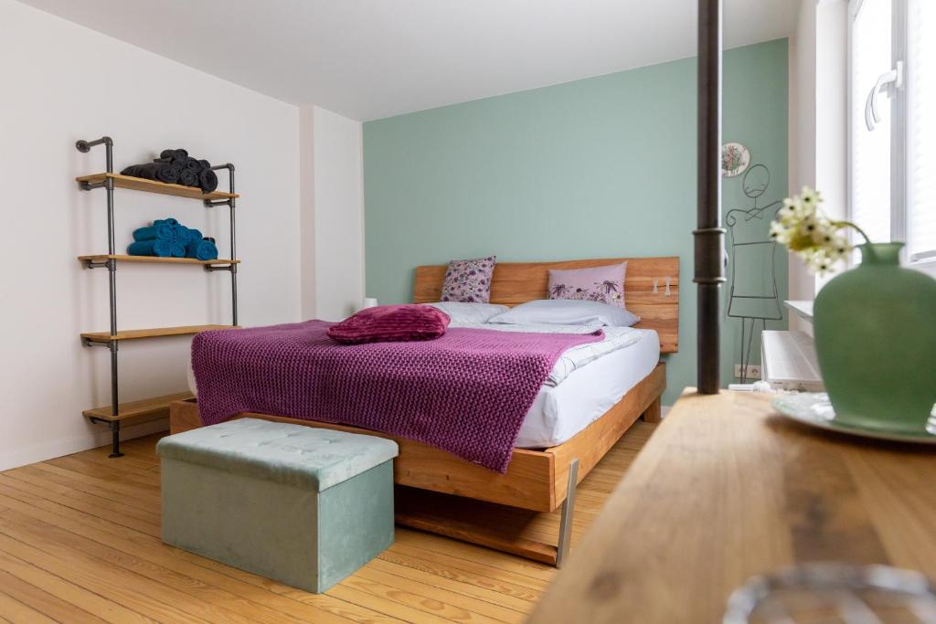 ein Schlafzimmer mit einem Bett mit einer lila Decke und einem Tisch in der Unterkunft Quartier Walzwerk in Püttlingen
