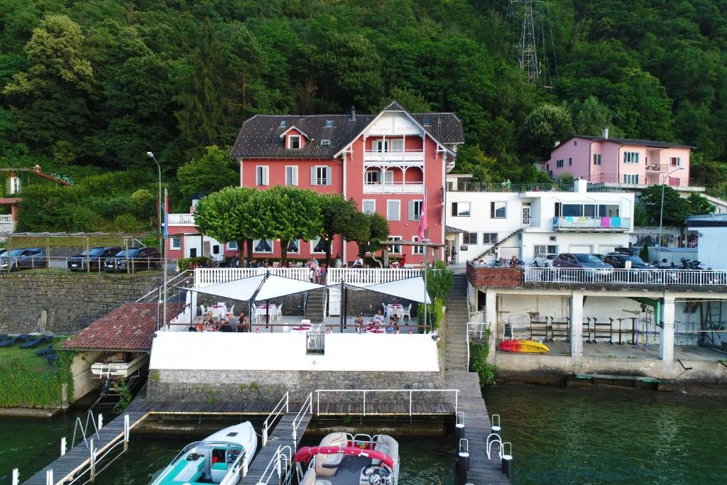 un groupe de bateaux amarrés dans un port de plaisance comportant des bâtiments dans l'établissement Zappa Lake Lodge, à Brusino Arsizio