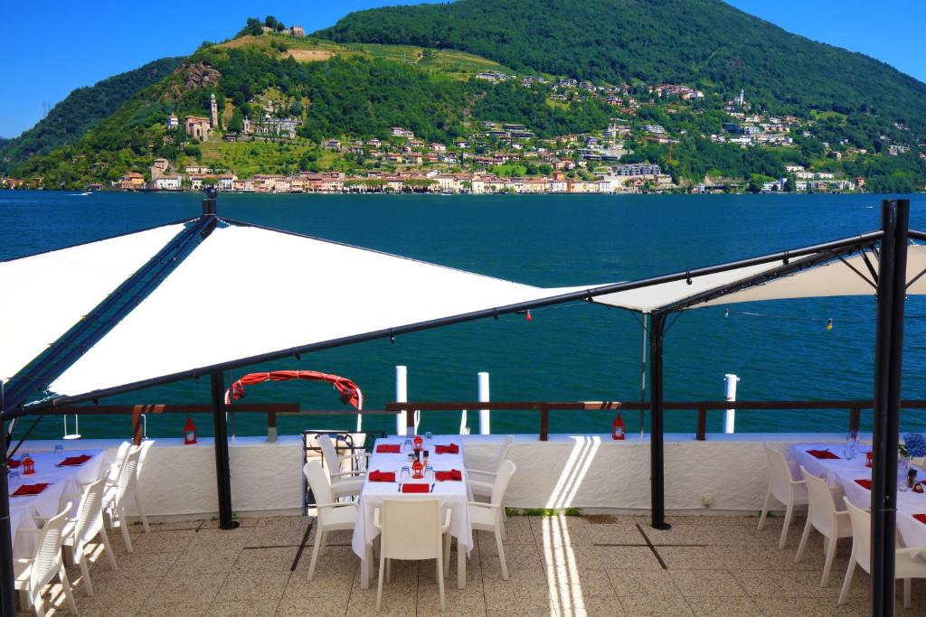 a table and chairs under a white tent next to the water at Zappa Lake Lodge in Brusino Arsizio