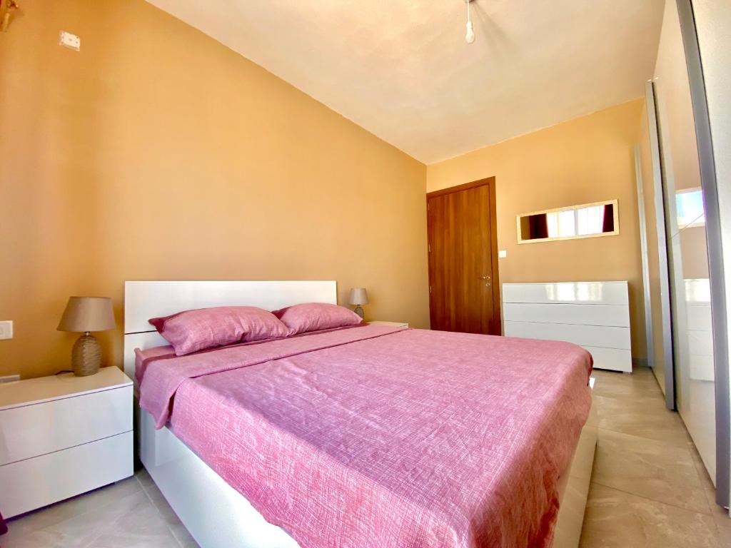 1 dormitorio con 1 cama grande con manta rosa en New Breeze en St Paul's Bay