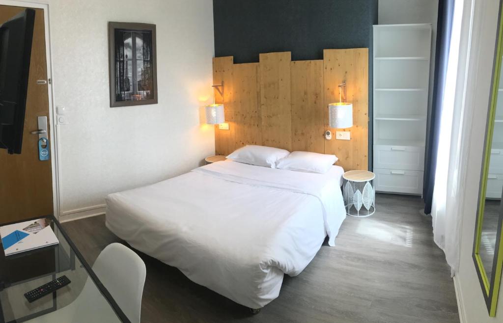 een slaapkamer met een groot wit bed in een kamer bij Hôtel du Maine in Parijs
