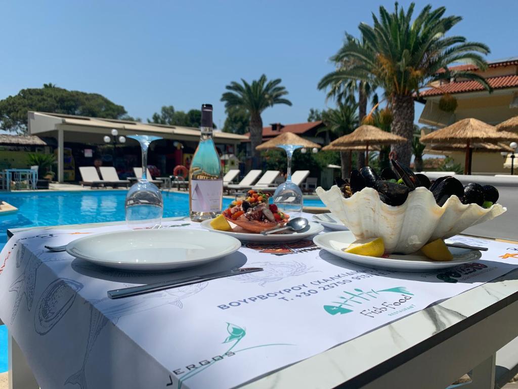 a table with plates of food next to a pool at Vergos Hotel in Vourvourou