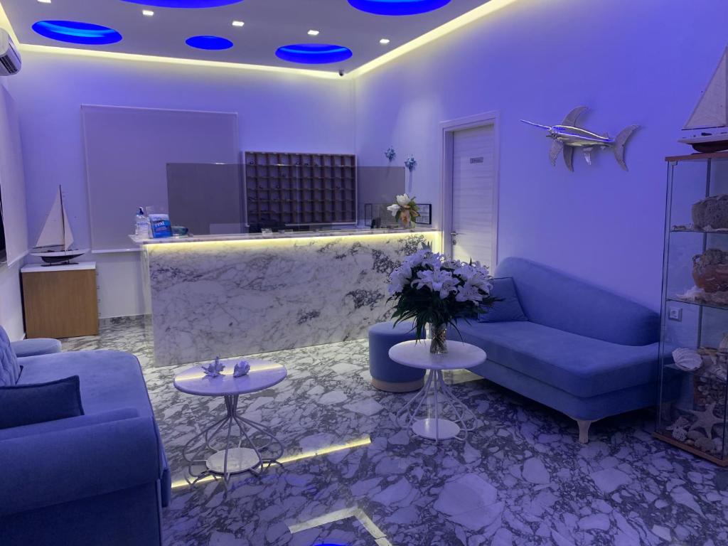 a living room with blue couches and flowers on tables at Vergos Hotel in Vourvourou