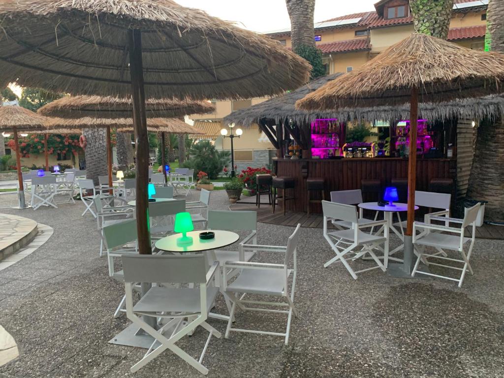 a patio with tables and chairs and umbrellas at Vergos Hotel in Vourvourou