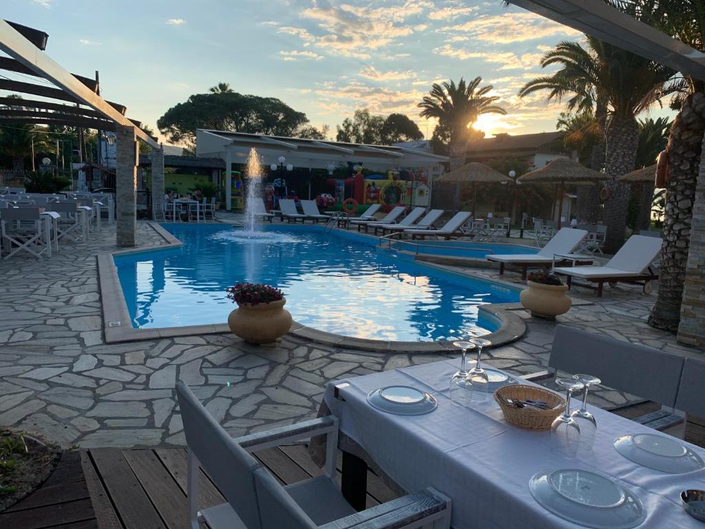 a swimming pool with a table and chairs and a table at Vergos Hotel in Vourvourou