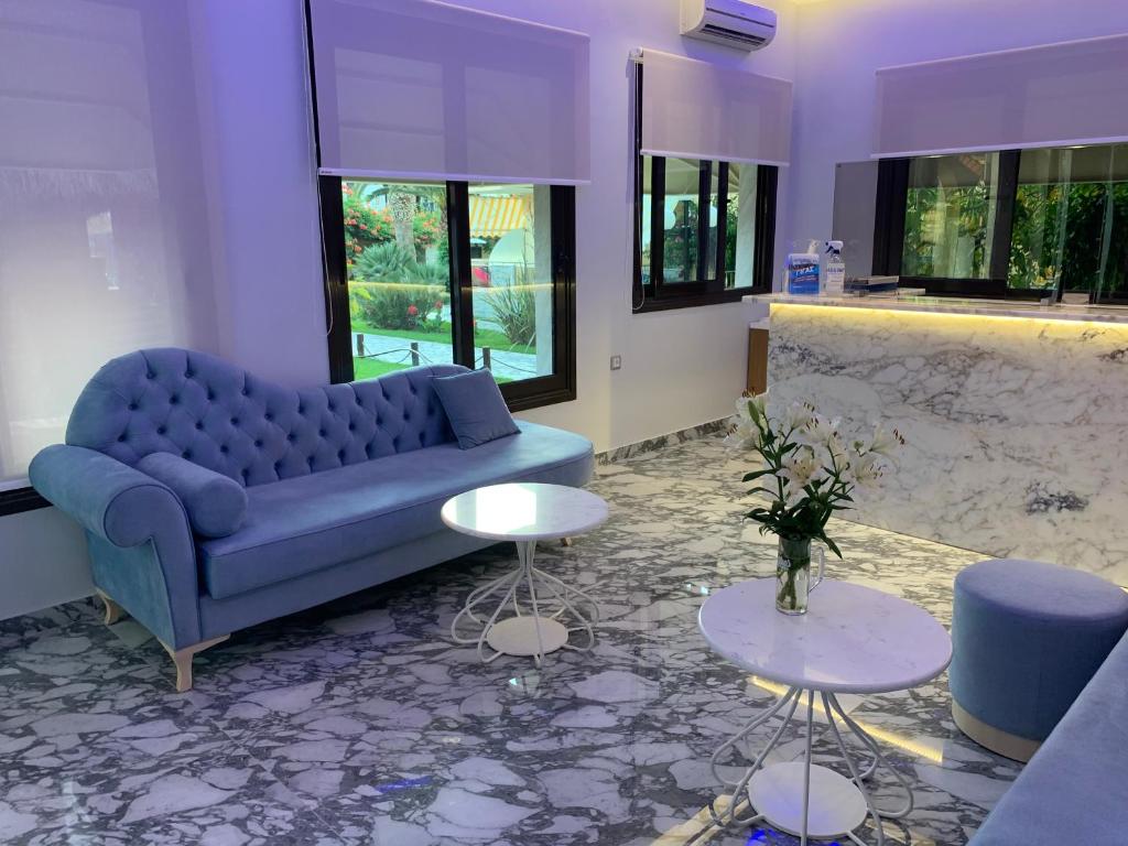 a living room with a blue couch and tables at Vergos Hotel in Vourvourou