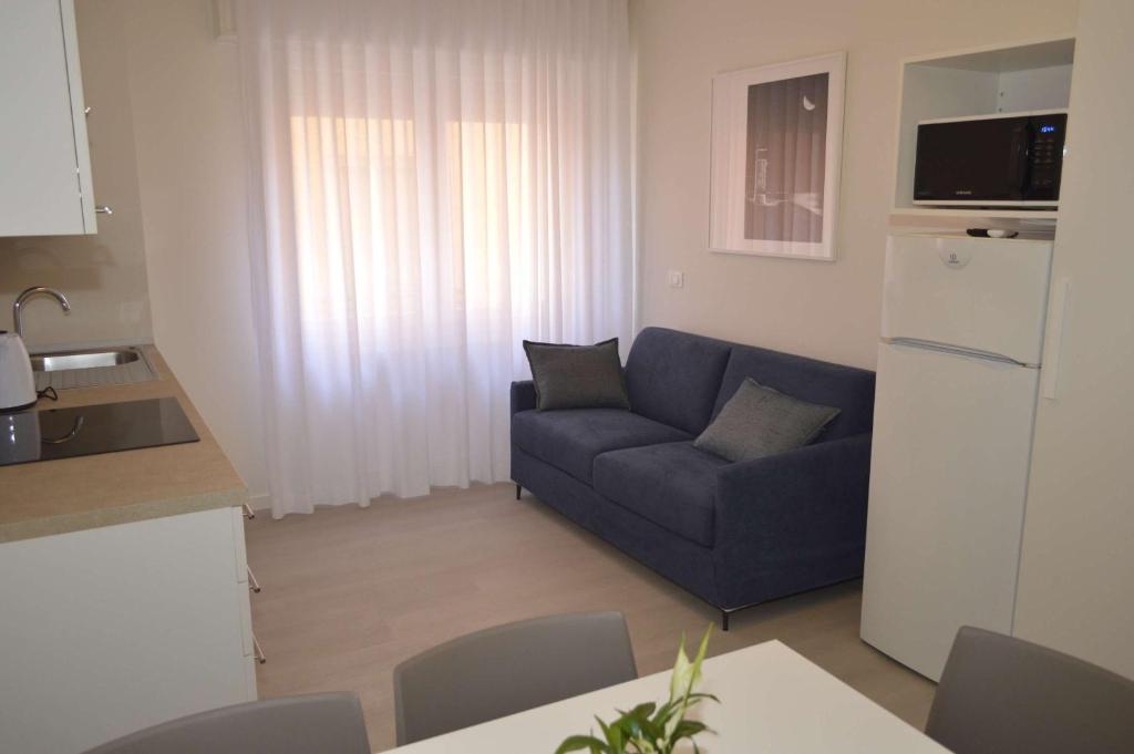 a living room with a blue couch and a kitchen at MAR60 Apartments in Caorle
