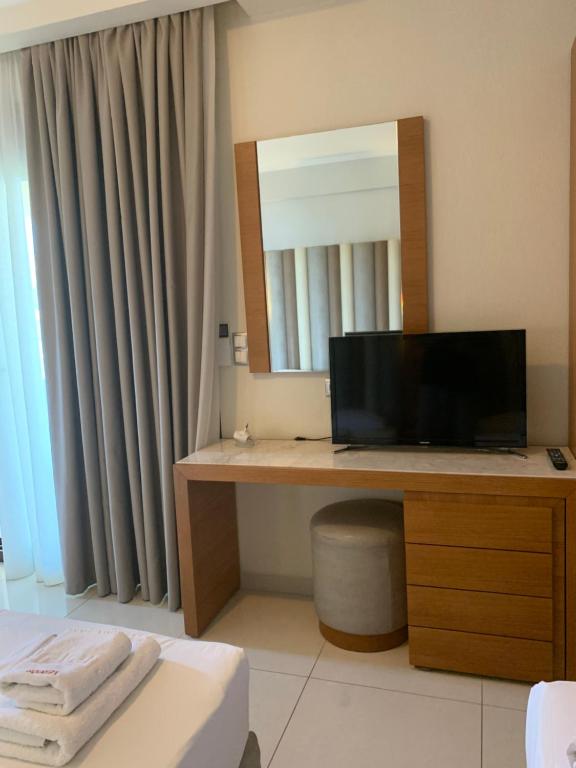 a room with a desk with a television and a mirror at Vergos Hotel in Vourvourou