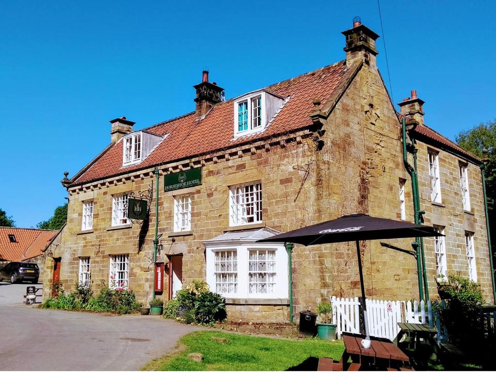 an old brick building with an umbrella in front of it at Horseshoe Hotel in Whitby