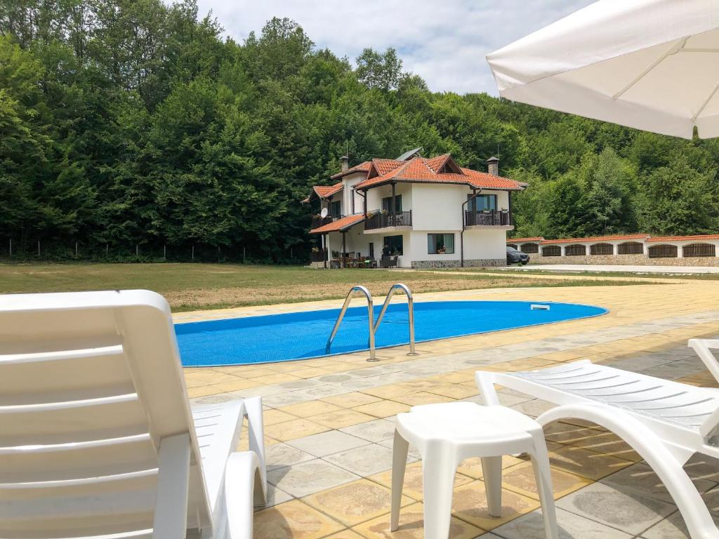 une maison dotée d'une piscine avec des chaises et un parasol dans l'établissement Wildwood Villa, à Apriltsi