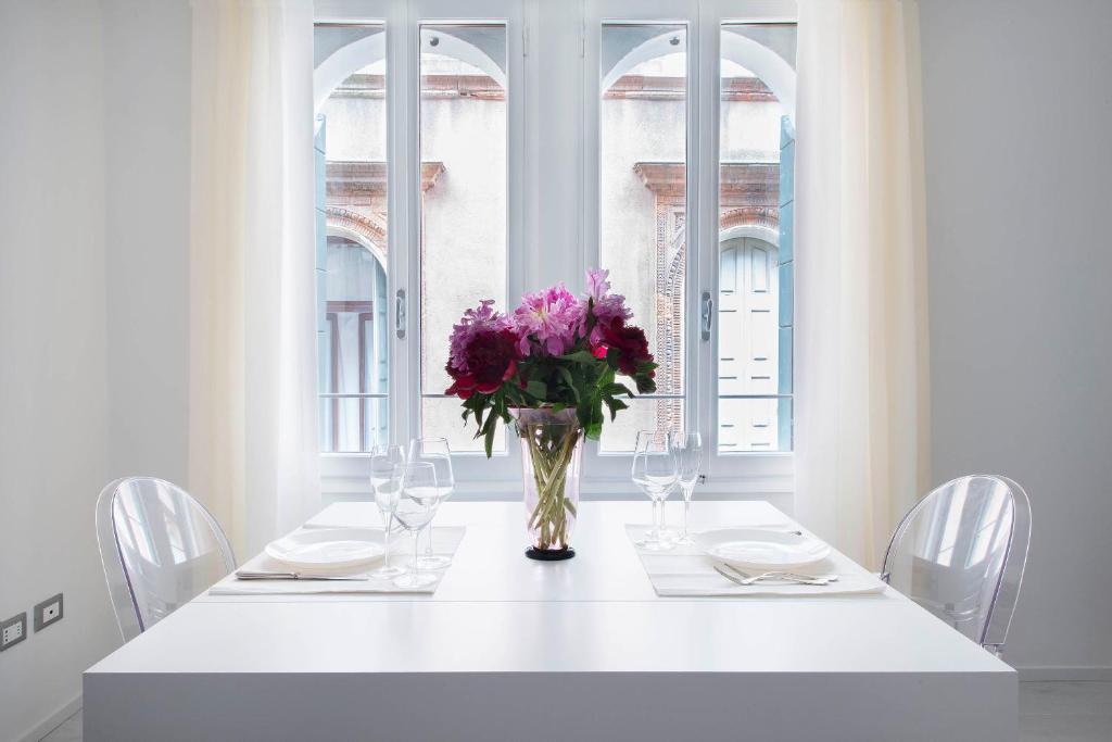 a white table with a vase of purple flowers on it at Ca Marta Venice in Venice