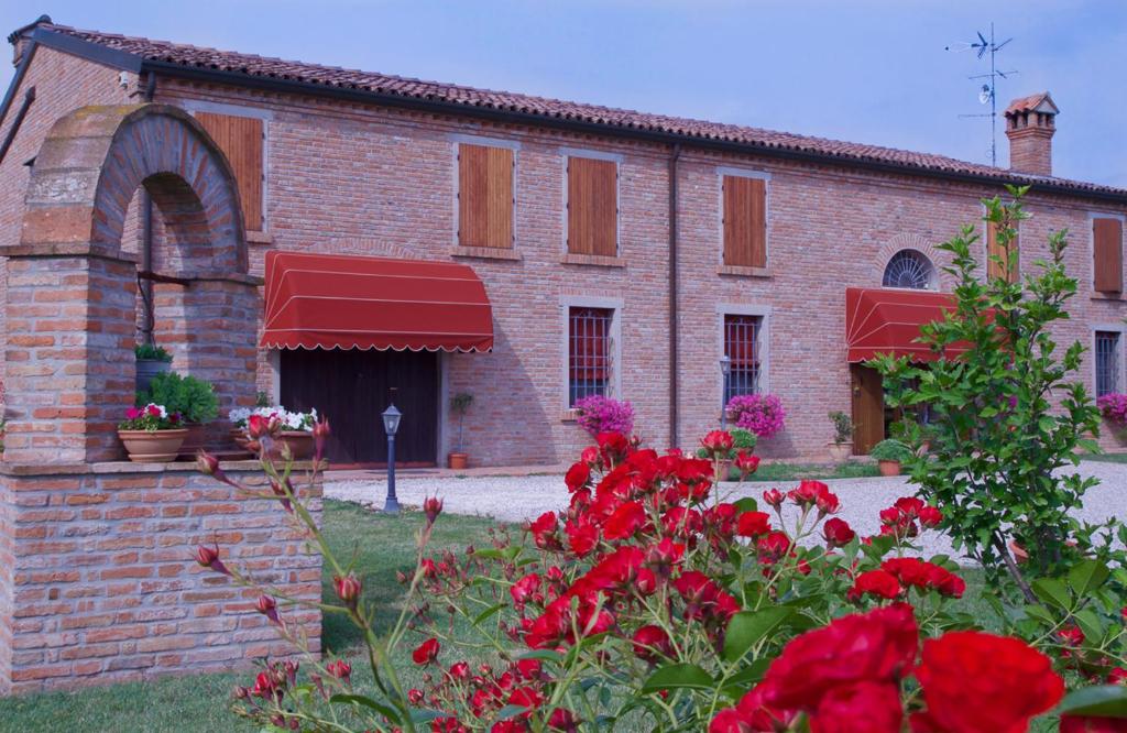 a brick building with red flowers in front of it at Il Frattiero B&B in Voghenza