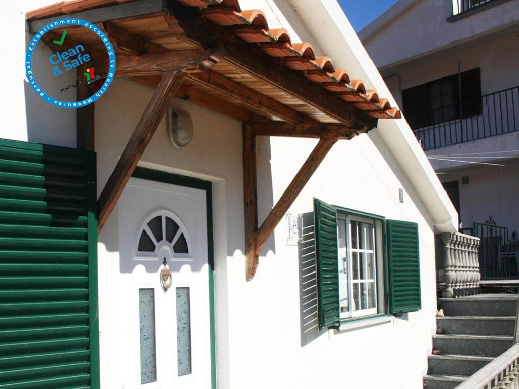 uma casa branca com persianas verdes e uma porta em Casa da Risca em Unhais da Serra
