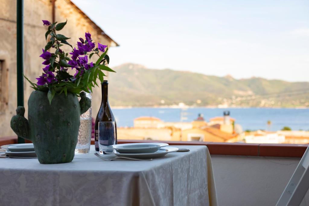 uma mesa com uma garrafa de vinho e flores roxas em Casa di Cosimo by HelloElba em Portoferraio