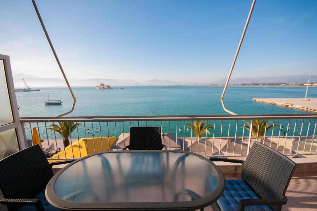 a table and chairs on a balcony with a view of the ocean at Di fronte alla fortezza in Nafplio