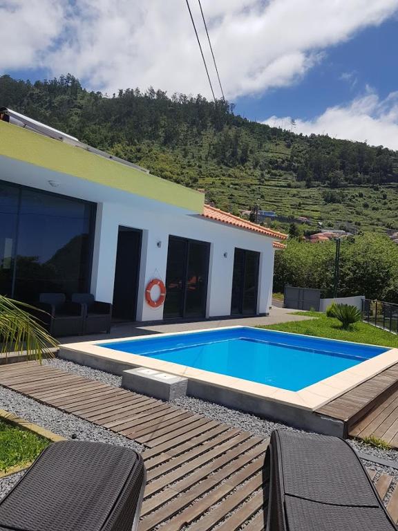 a swimming pool in front of a house at migs'place in Arco da Calheta