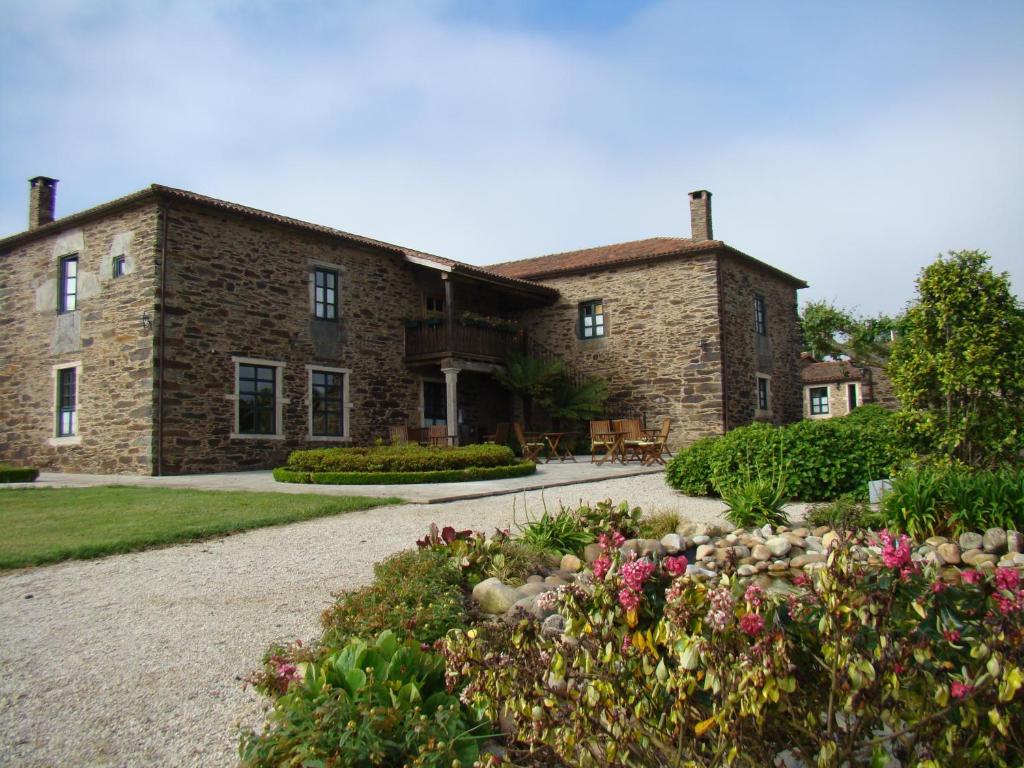 a stone house with a garden in front of it at Pazo Santa María in Arzúa