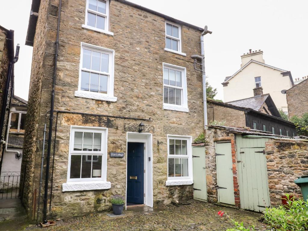 una vieja casa de ladrillo con una puerta azul en Pine Cottage en Sedbergh