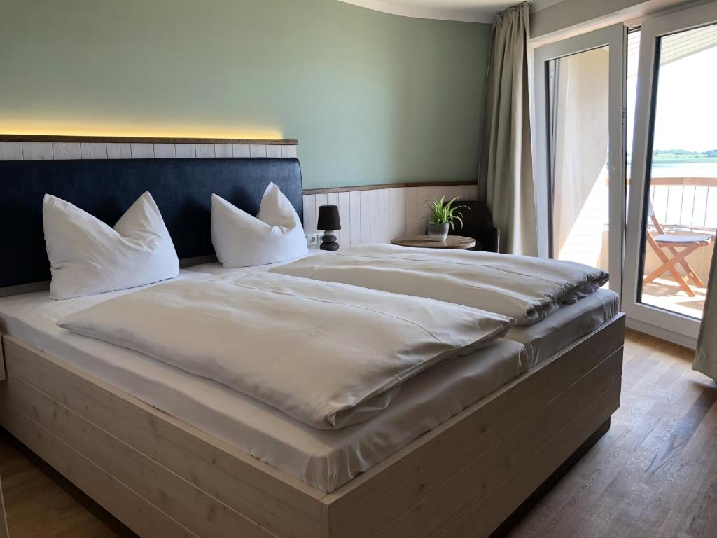 duże łóżko z białą pościelą i poduszkami w sypialni w obiekcie BE BIO Hotel be natural w mieście Tönning