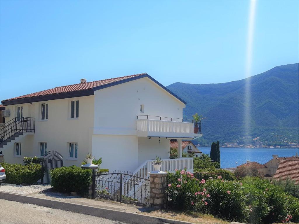 a white house with a balcony and a lake at Apartments Sonja in Kotor