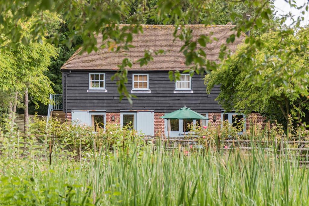 een zwart huis met een groene paraplu ervoor bij Great Higham Oast and Cottages by Bloom Stays in Canterbury