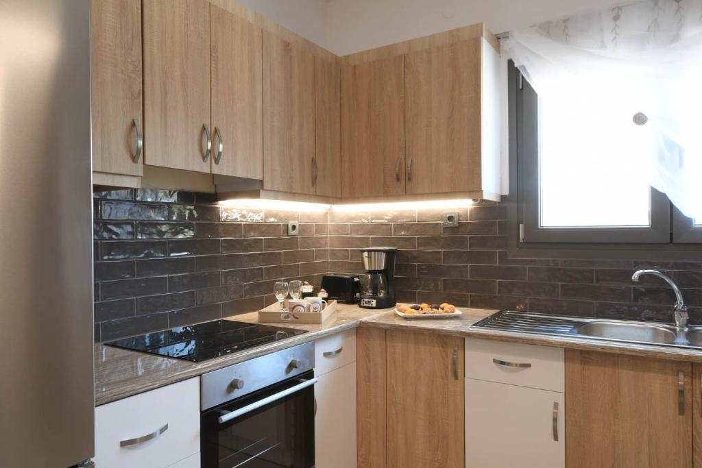 a kitchen with wooden cabinets and a sink at Orion Eco Suites in Karteros