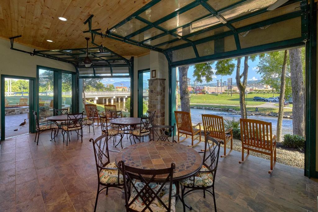 a dining room with tables and chairs and windows at The Inn On The River in Pigeon Forge